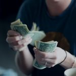 income focus photography of person counting dollar banknotes