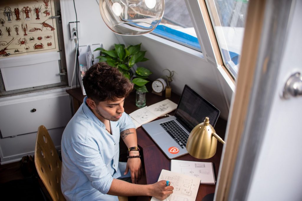remote working man sits while writing in front of MacBook