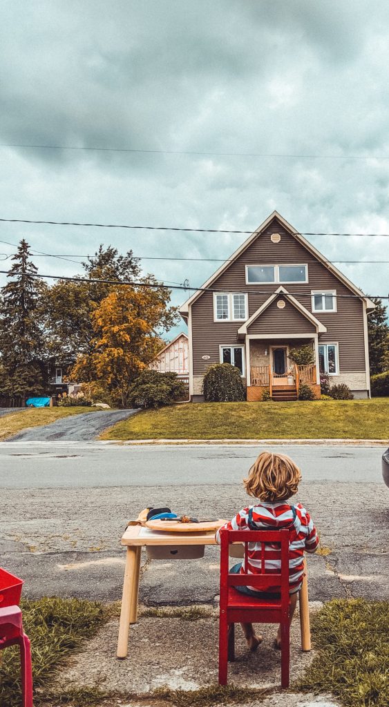 selling a house boy sitting on red chair facing near house