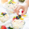 fruit salad recipes person holding blueberry fruit with hands on top of fruit salad