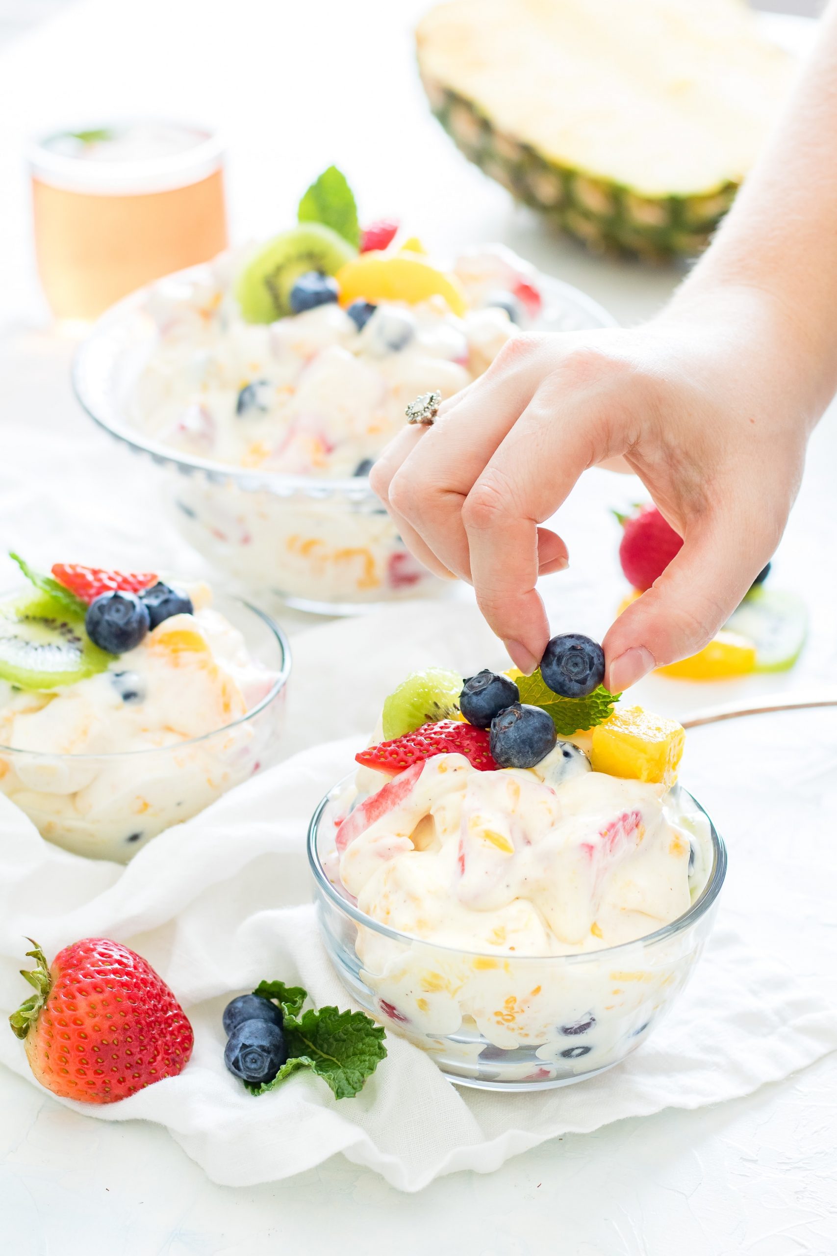 fruit salad recipes person holding blueberry fruit with hands on top of fruit salad
