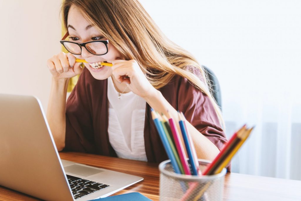 mental health woman biting pencil while sitting on chair in front of computer during daytime