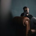 mental health a man holds his head while sitting on a sofa