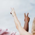 Gender Equity woman in white and pink floral shirt raising her hands