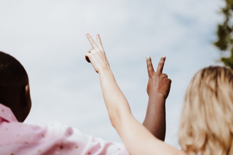 Gender Equity woman in white and pink floral shirt raising her hands