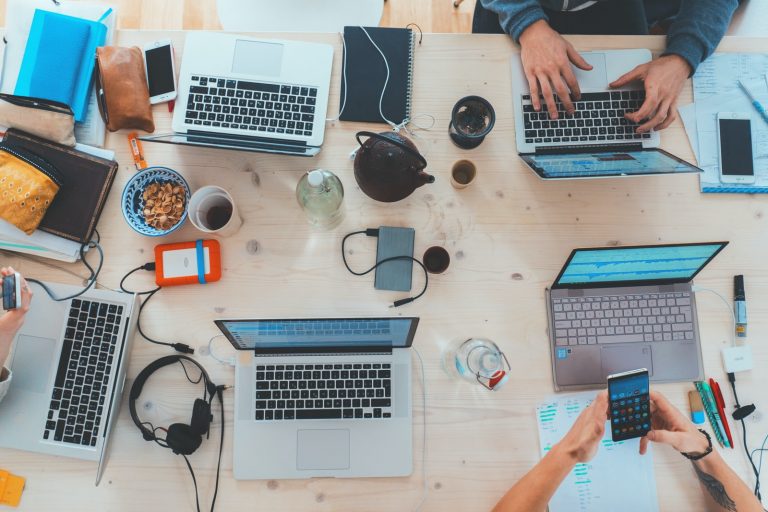 digital marketing people sitting down near table with assorted laptop computers