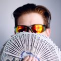 SSS unemployment benefits man in black framed sunglasses holding fan of white and gray striped cards