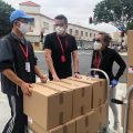 courier service 3 men in black polo shirt standing beside brown cardboard boxes