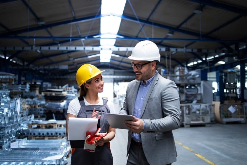 A person and person wearing hard hats and holding a tablet
