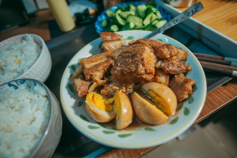 Filipino Food Business Ideas- A plate of Filipino pork adobo with boiled eggs served alongside rice and fresh vegetables.