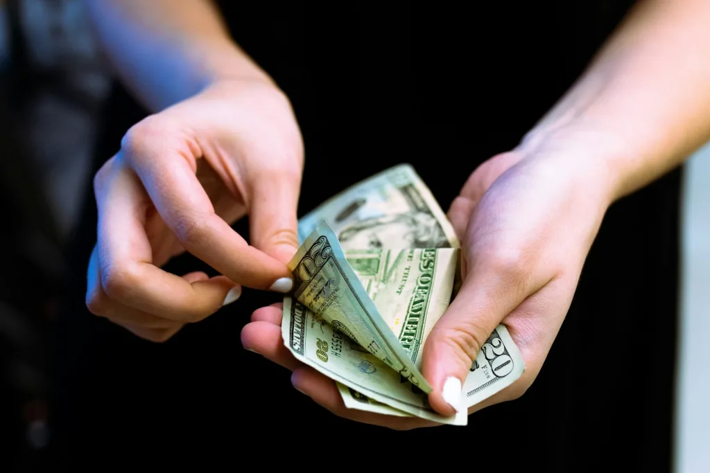 Tips for First-Time Borrowers on Using a Small Business Loan Wisely 1 person holding fan of 100 us dollar bill